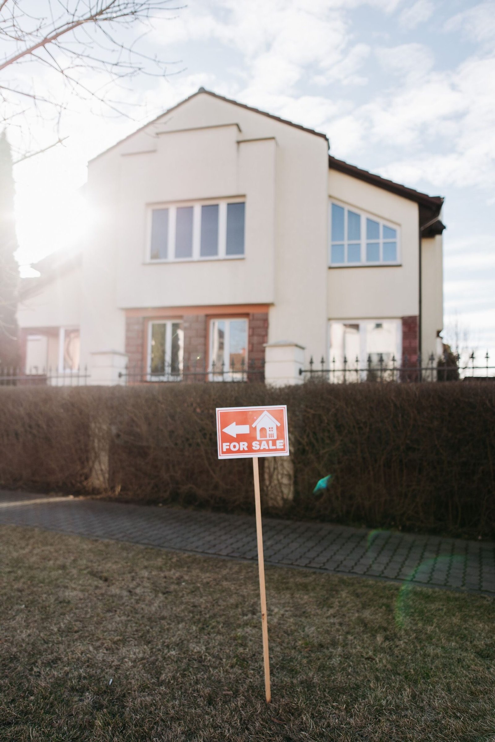A for-sale sign in front of a suburban house