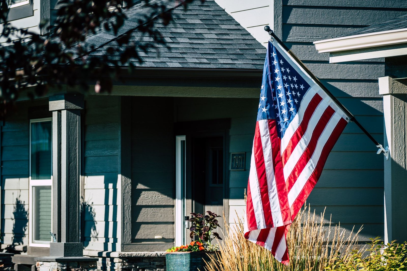 American flag flying from the porch of a suburban home