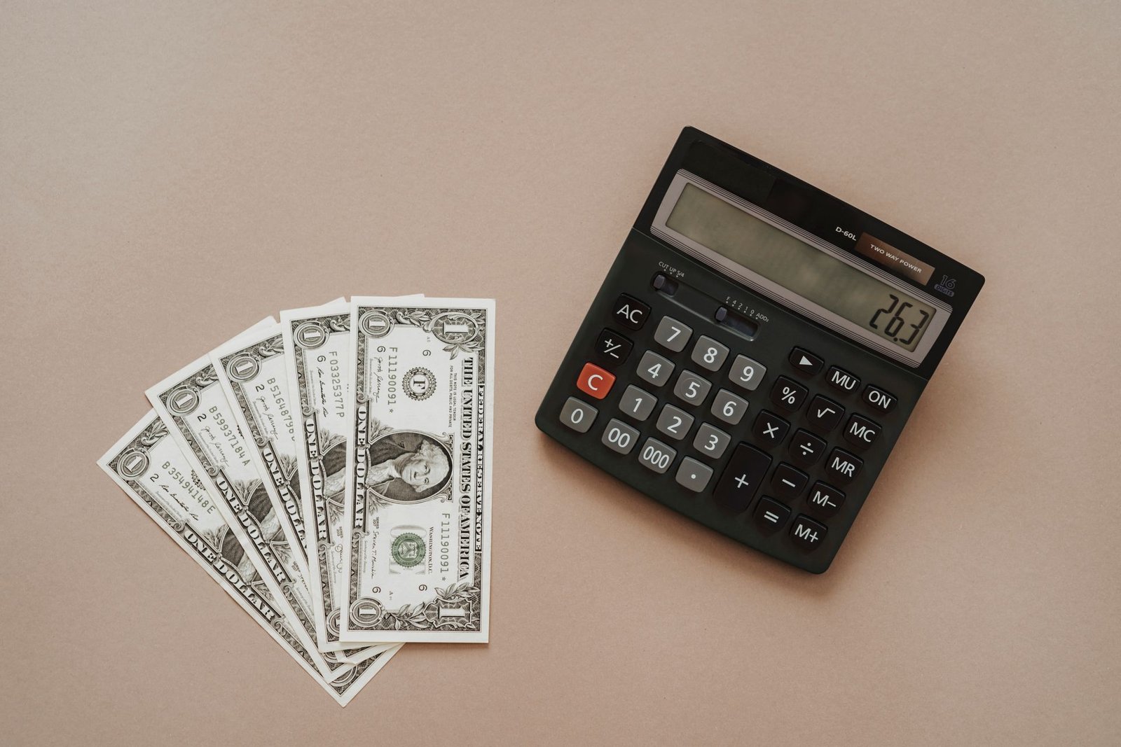 Desktop calculator next to fanned US dollar bills