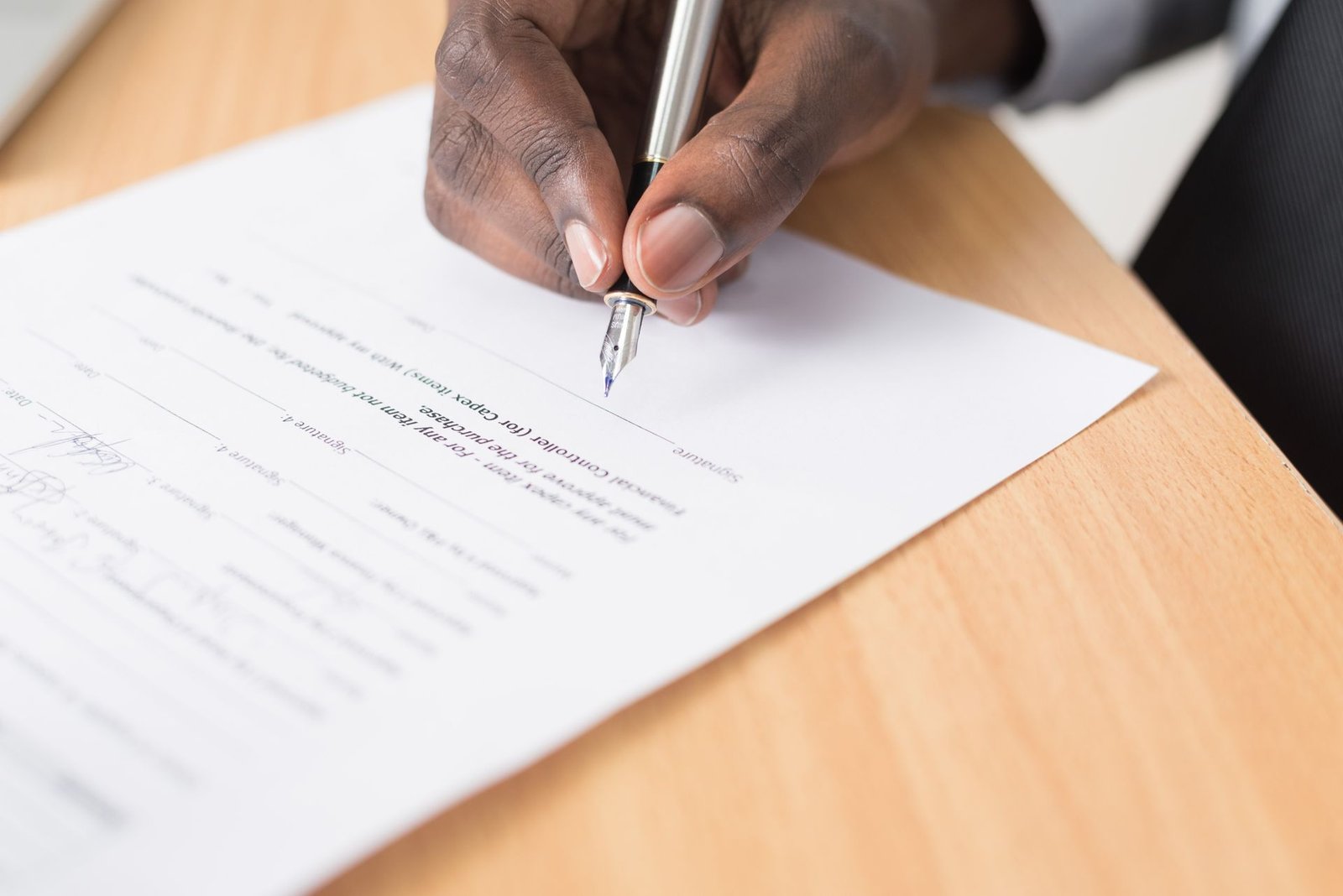 Person signing car loan paperwork with a pen